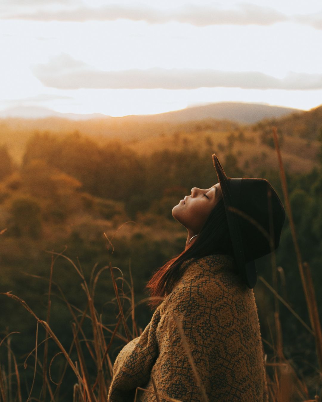 Woman Wearing Brown Cardigan and Black Hat with her face to the sky