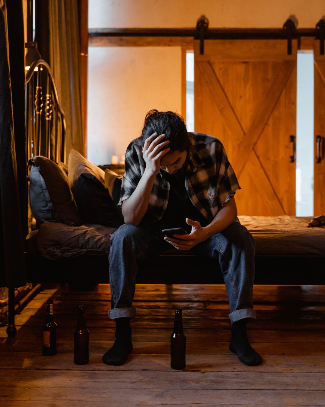 Stressed Man Sitting on the Bed with his phone in his hand